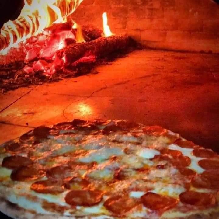 Imagem de uma pizza sendo preparada em um forno a lenha